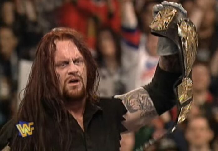 A victorious Undertaker holds up the WWF Championship belt at WrestleMania 13