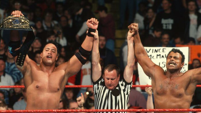 The ref holds up the arms of The Rock and Rocky Johnson at WrestleMania 13