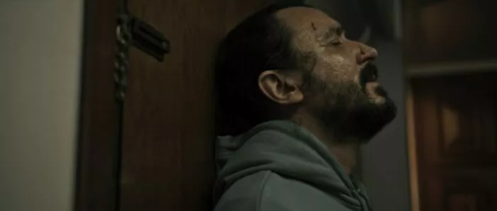 A man leaning against a door