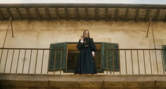 A woman waving from a balcony