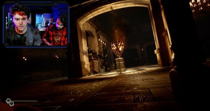 Two men are seen covered in blood in the top right corner of the screen while the rest of the screen shows a video game image of a bloody hallway in Livescreamers