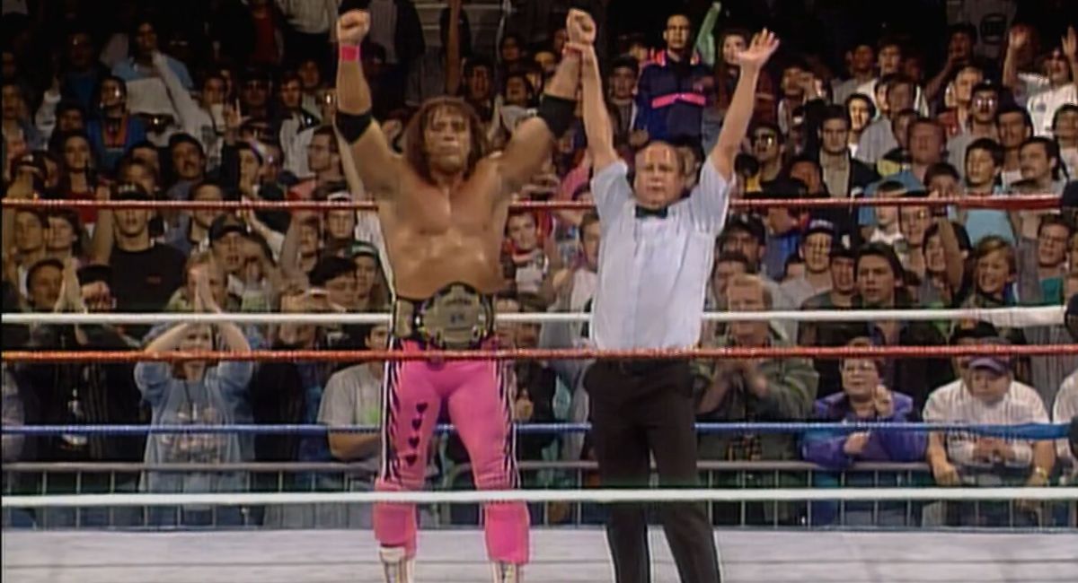 Bret Hart, with the WWF championship around his waist, has his hand held high by referee Earl Hebner.