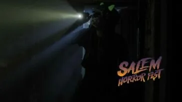 A masked individual holds a flashlight over their shoulder while entering a dark room in GHOST GAME