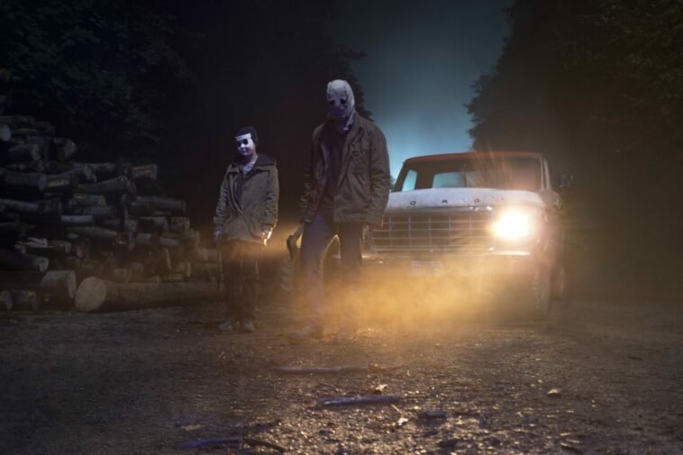 Two masked killers standing by a car