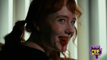 A red-headed womansmiles over her shoulder revealing a mouth full of blood dripping off her teeth and lips in CANNIBAL MUKBANG