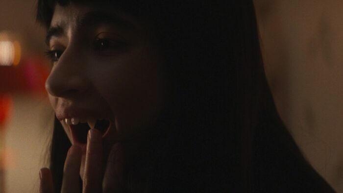 a girl touches her pertruding fangs 