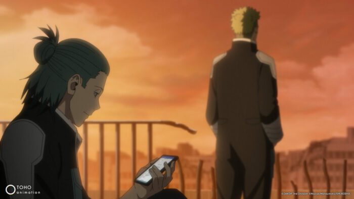 A man checking his cellphone with another man in the background