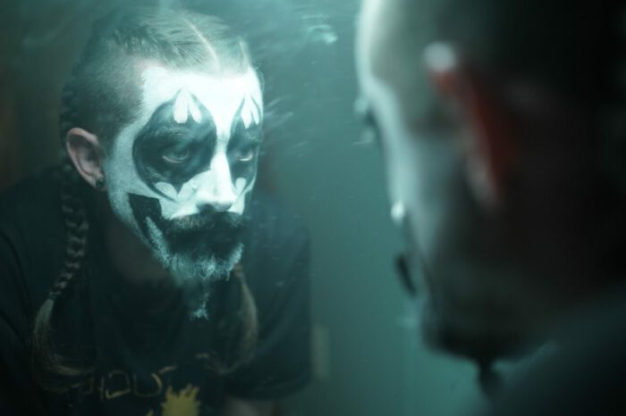 a man wearing clown makeup looks into the mirror