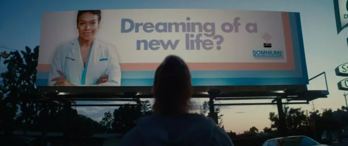 The silhouette of a woman at sundown looking at a billboard in SOMNIUM