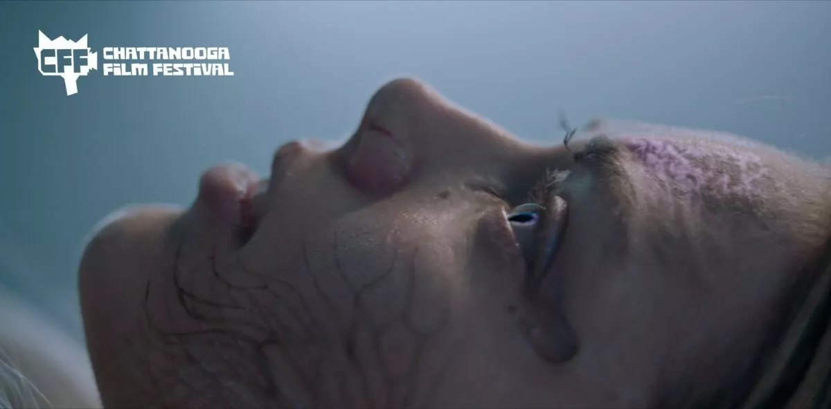 Side profile of a woman's face, facing up from a lying down position, with a darkness growing in her veins