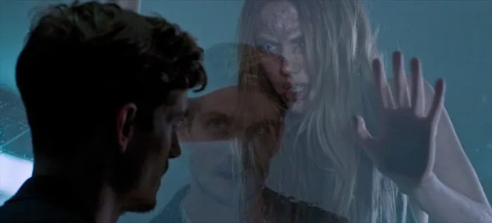 A woman bangs on a glass divider where a man is observing her in THE FIX.