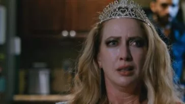 A woman wearing a crown and looking distressed