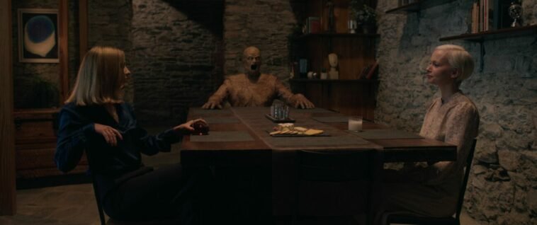 Two women at a table with a wooden mannequin