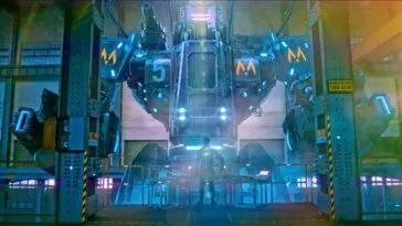 A man looks up at the face of a large mech-robot.