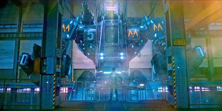 A man looks up at the face of a large mech-robot.