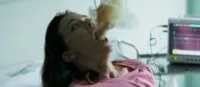 A woman in a hospital bed expels smoke.