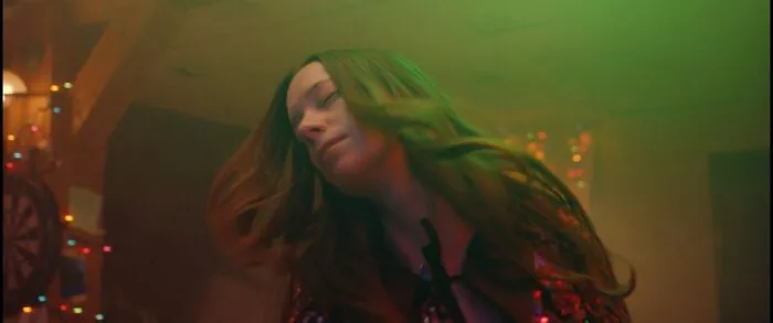 A woman with her eyes closed sways, making her hair sway in Kryptic.