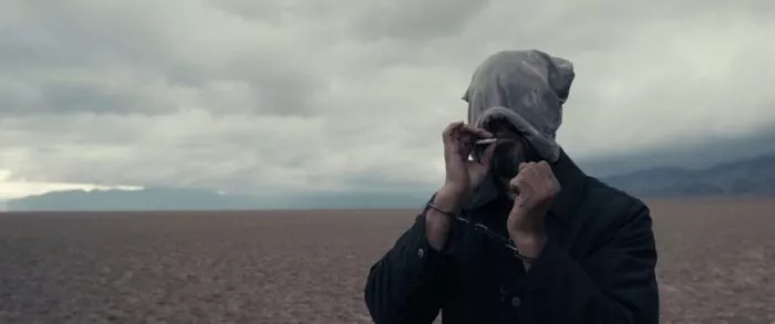 A man with a bag over his head smoking a cigarette