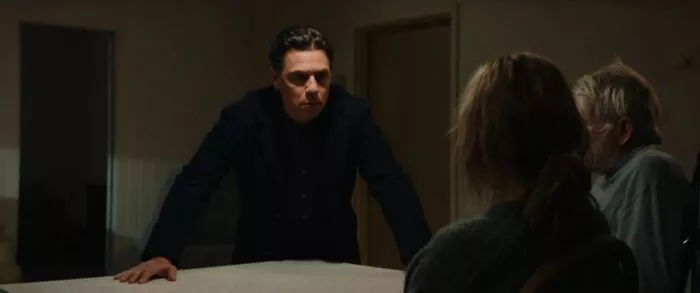 A man talking to a couple from across a table