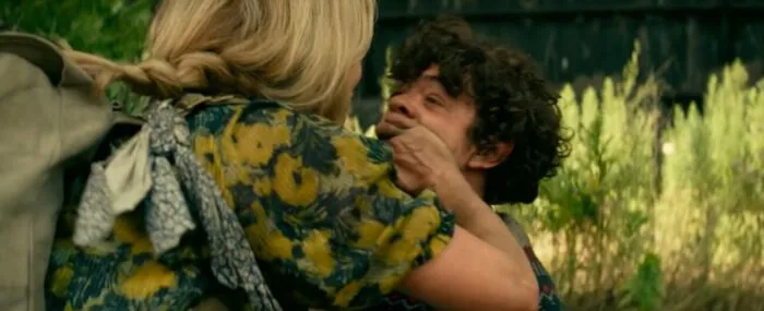 Evelyn covering her son's mouth while he screams