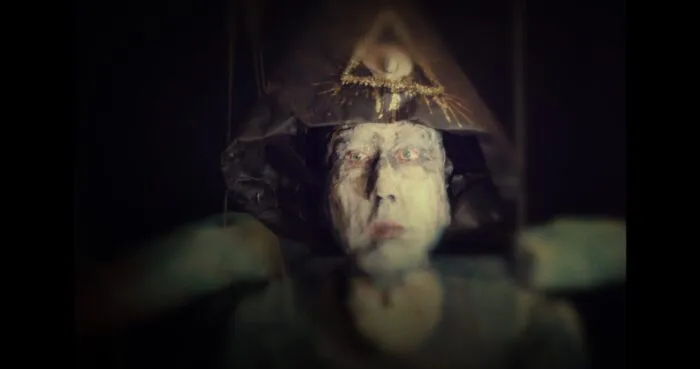 A pale man wearing a hat with the all-seeing eye image on it