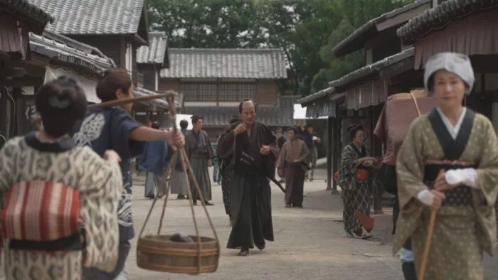 A robe adorning man walks through an ancient village in Japan