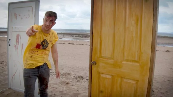 A man standing next to a door on a beach