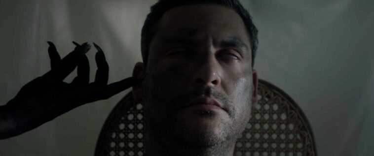 A demonic hand touching a man's face