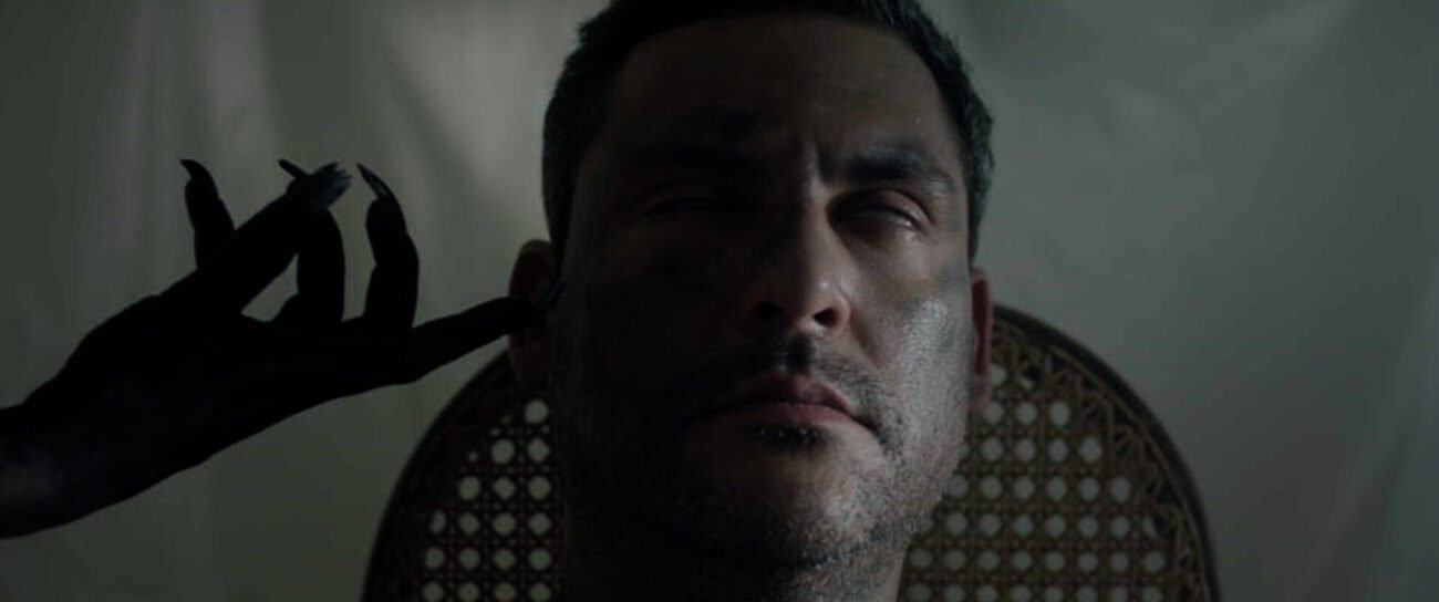 A demonic hand touching a man's face