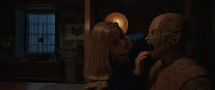 A woman puts her hand into the mouth of a man-sized wooden figure in Odditty