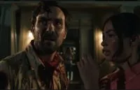 A man looks quizzically away from the woman next to him, a little girl appears in the doorway in the background.