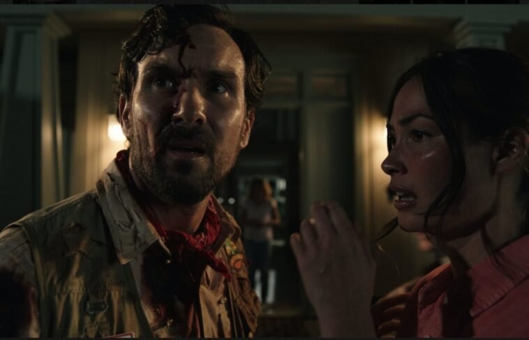 A man looks quizzically away from the woman next to him, a little girl appears in the doorway in the background.