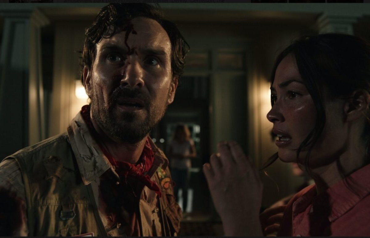 A man looks quizzically away from the woman next to him, a little girl appears in the doorway in the background.
