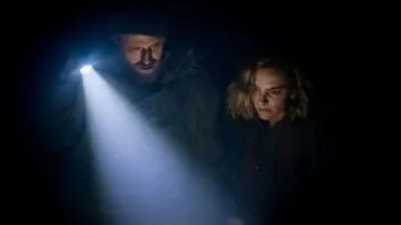 a man holding a flashlight stands beside a woman