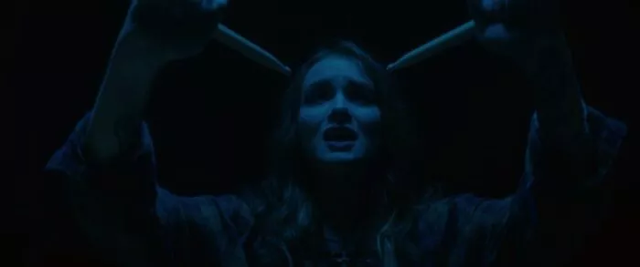 A woman about to stab herself with drumsticks