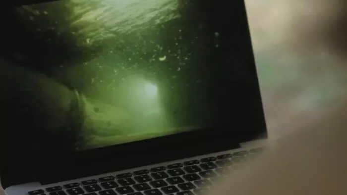 A camera films the laptop which shows Chad in the caves