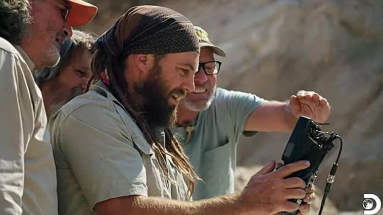 A group of men smiling while looking at a monitor