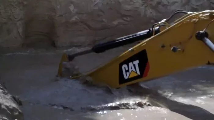 Duane uses the CAT excavator to rip up the reinforced pipe