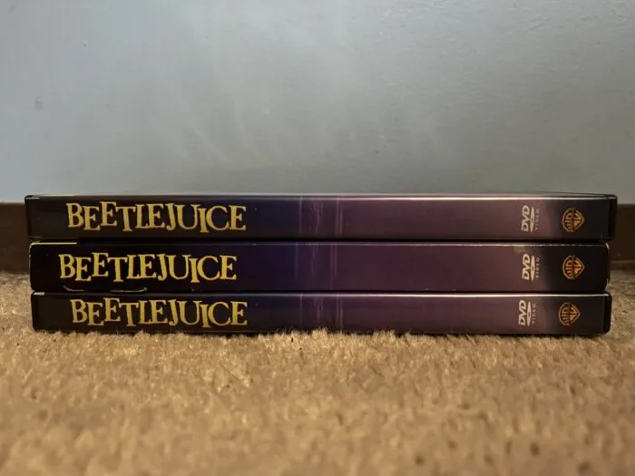 Three DVD cases for the film, “Beetlejuice” (1988), stacked on top of each other.