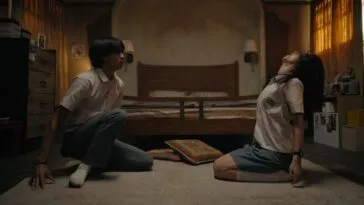 Two people sitting on the floor, with one of them getting possessed