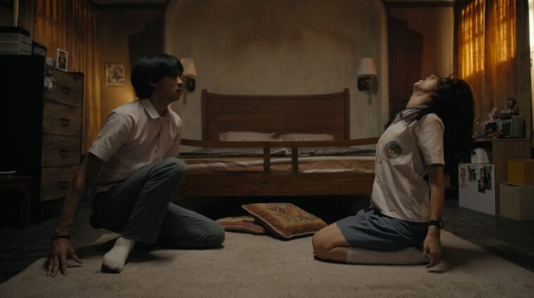 Two people sitting on the floor, with one of them getting possessed