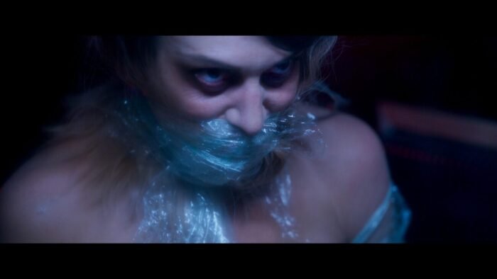 A woman's face and body are wrapped in plastic.