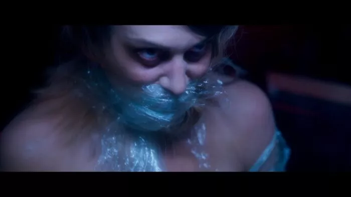 A woman's face and body are wrapped in plastic.