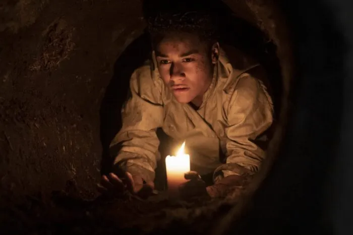 A woman holding a candle in a tunnel