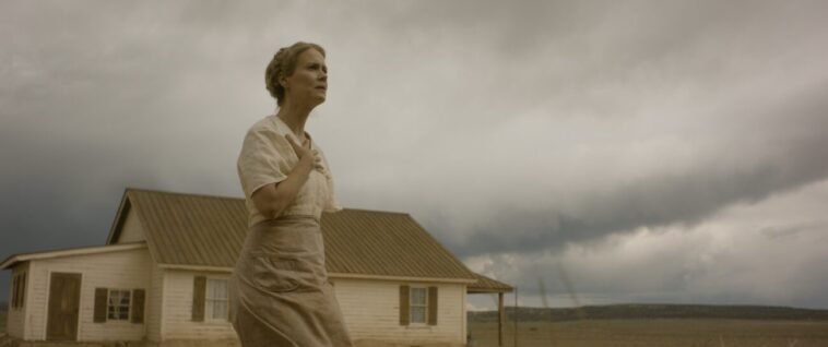 A woman is seen outside of a house under a threatening sky in HOLD YOUR BREATH