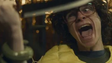 A young man holding a butcher's knife has his hand wrapped up by a tendril