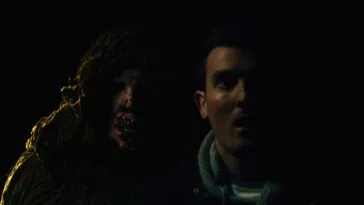 a hooded figure approaches over a man's right shoulder in Beyond the Woods