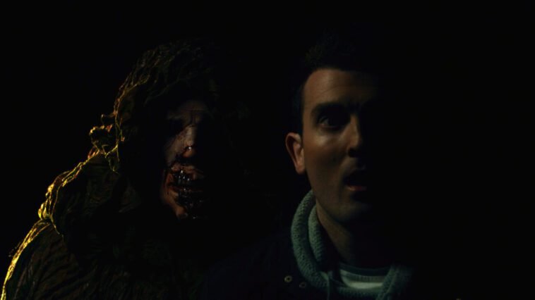 a hooded figure approaches over a man's right shoulder in Beyond the Woods