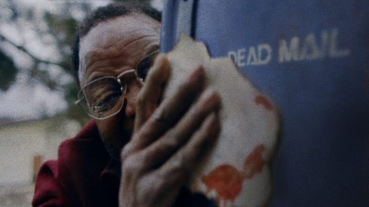 A man holding a letter by a mailbox