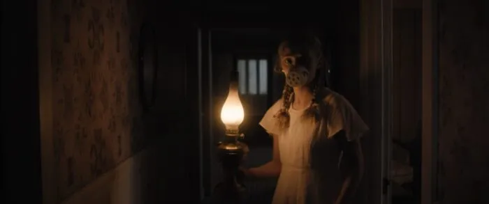 a young woman with a makeshift breathing mask on carries a lantern around a dark house in HOLD YOUR BREATH
